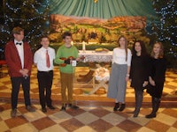 a group of people standing in front of a christmas tree