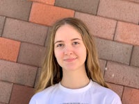 a young woman wearing a white t - shirt in front of a brick wall