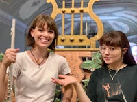 two women standing next to a harp in a museum